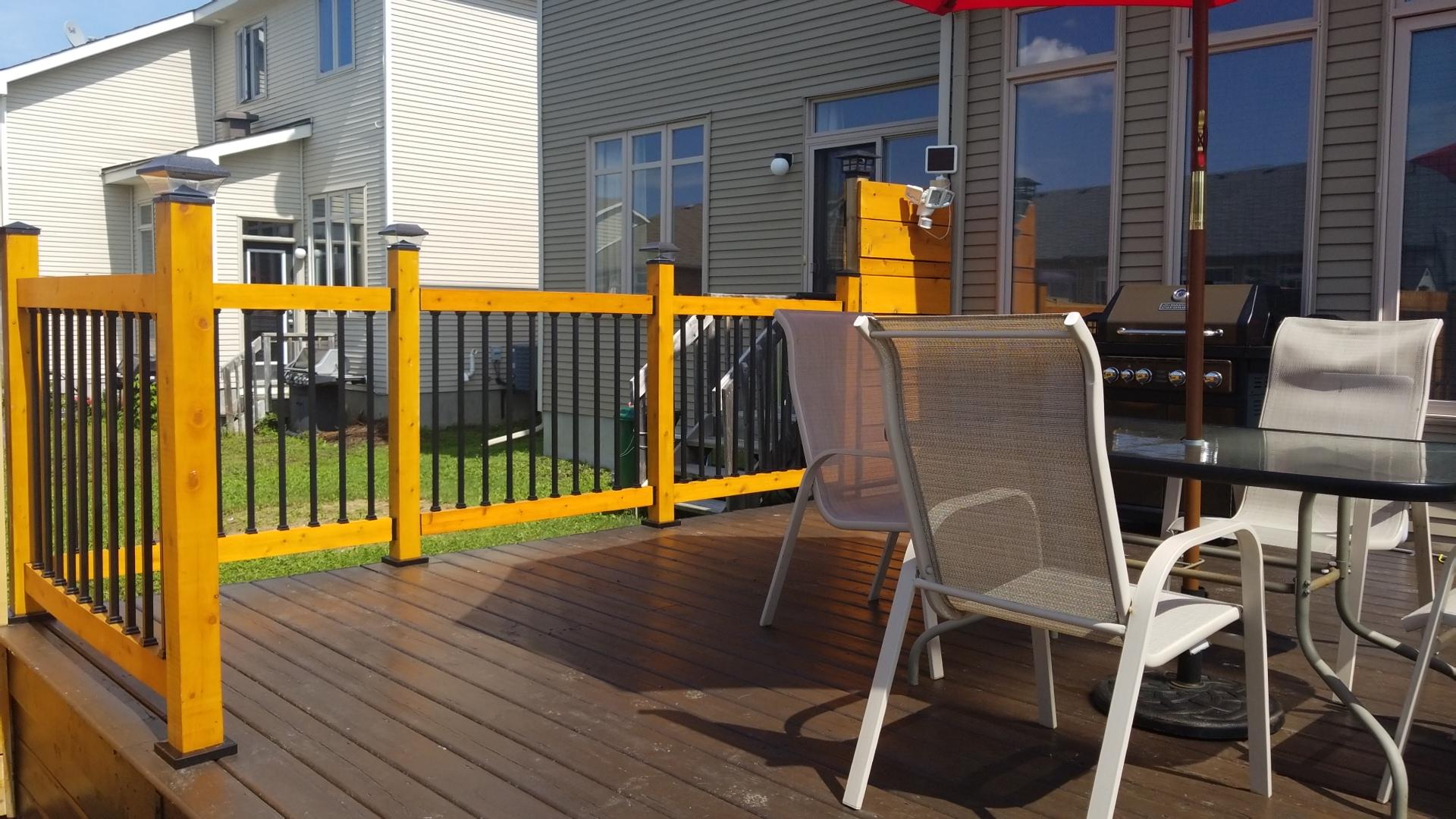 Low level wooden deck with patio furniture potted plants and an umbrella