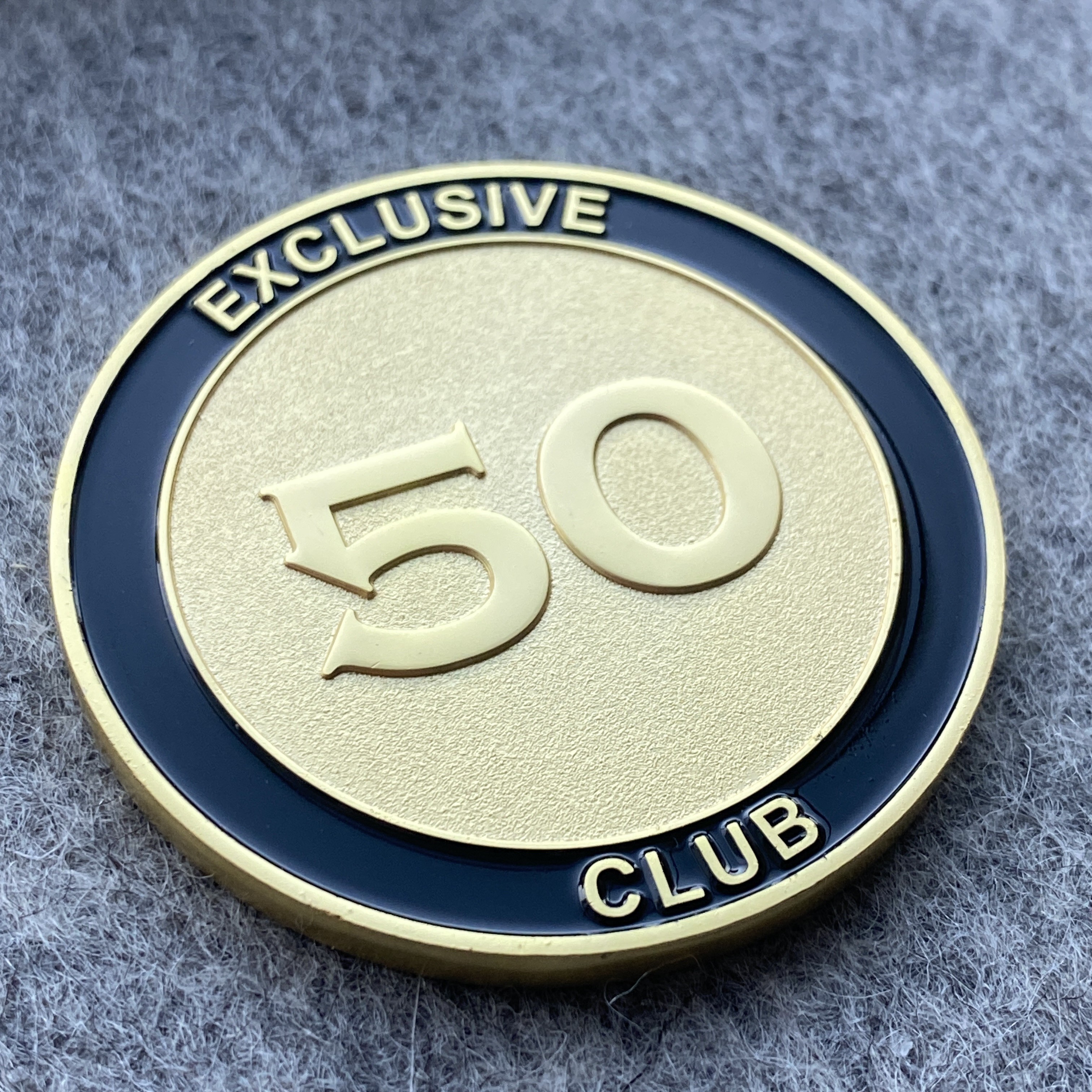 Gold and dark blue metal coin with number 50 and two words
