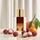 Soleil Invisible bottle with lychees and mandarins against a cream pleated curtain