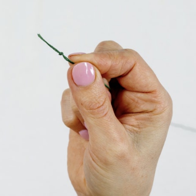 An knotted embroidery thread is held up.