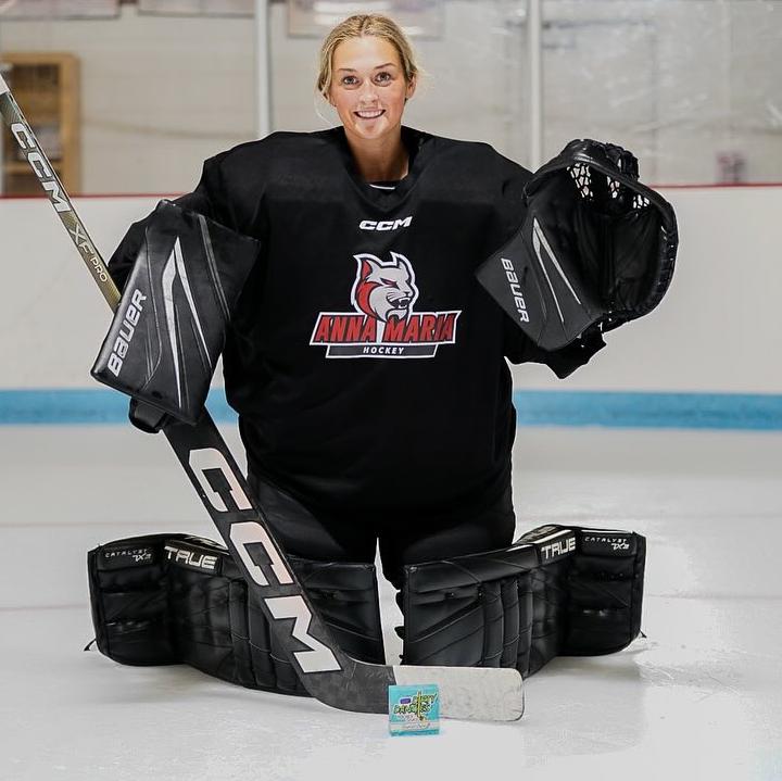 Women’s hockey goalie on the ice with Dirty Dangles hockey soap in front of the net.