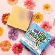 a bar of dirty dangles natural hockey soap for women on a pink background with flowers