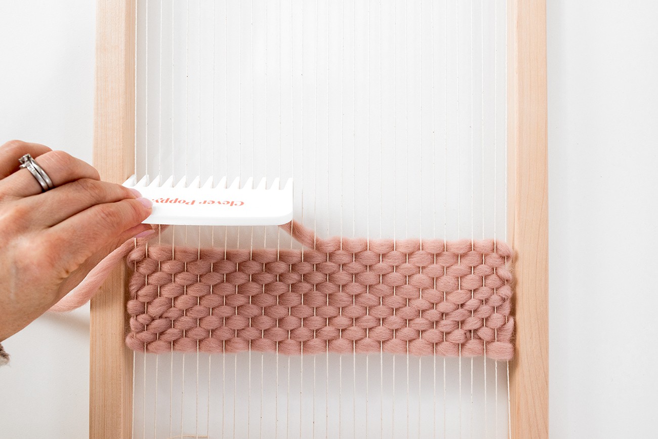 A comb brushes down rows of tabby weave.