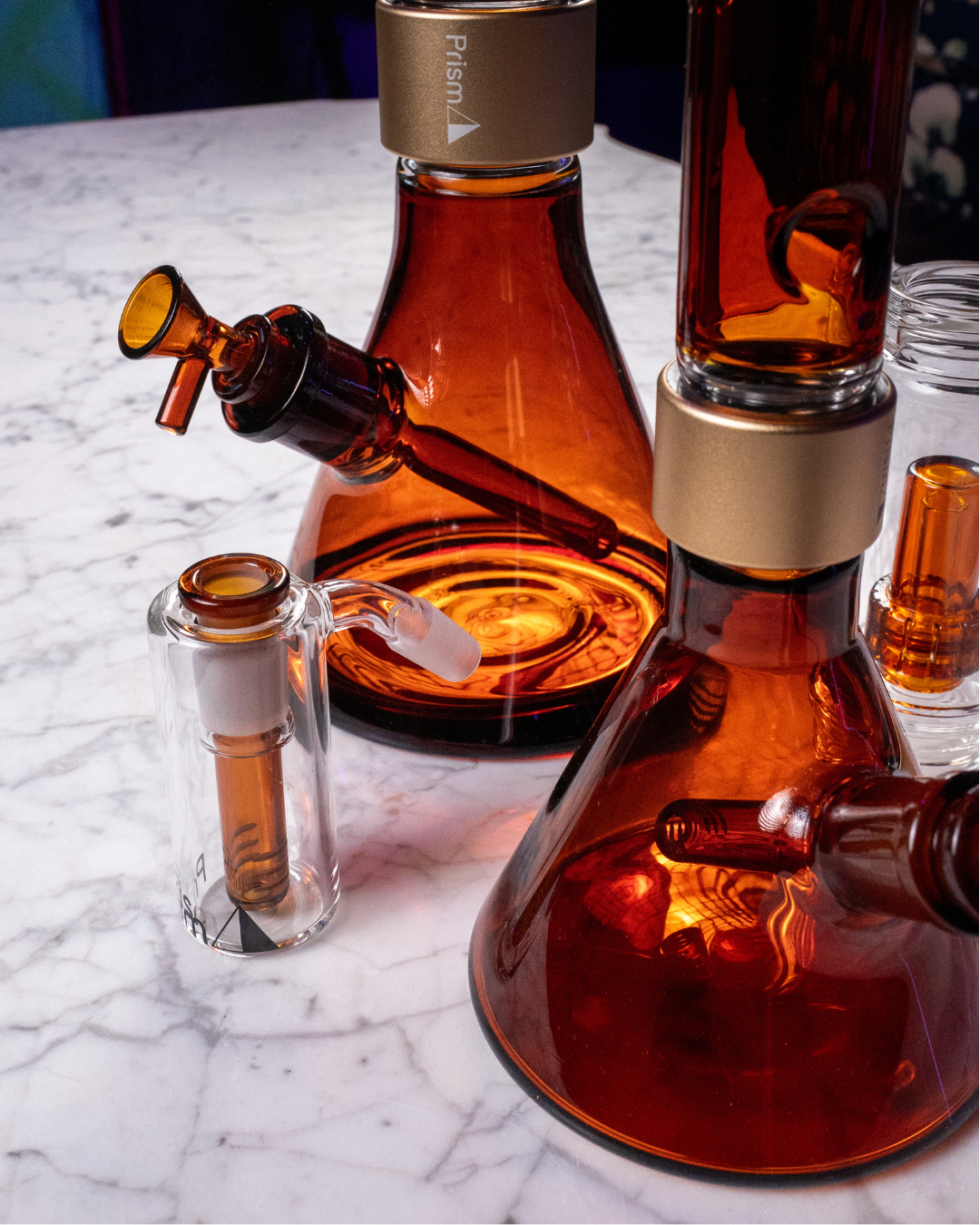 A close-up of the Prism Amber Collection modular components arranged on a luxury white marble surface. The shot showcases the rich honey tones and high-clarity borosilicate glass, illustrating how the collection functions as a sophisticated home decor accent for modern, elevated interiors.