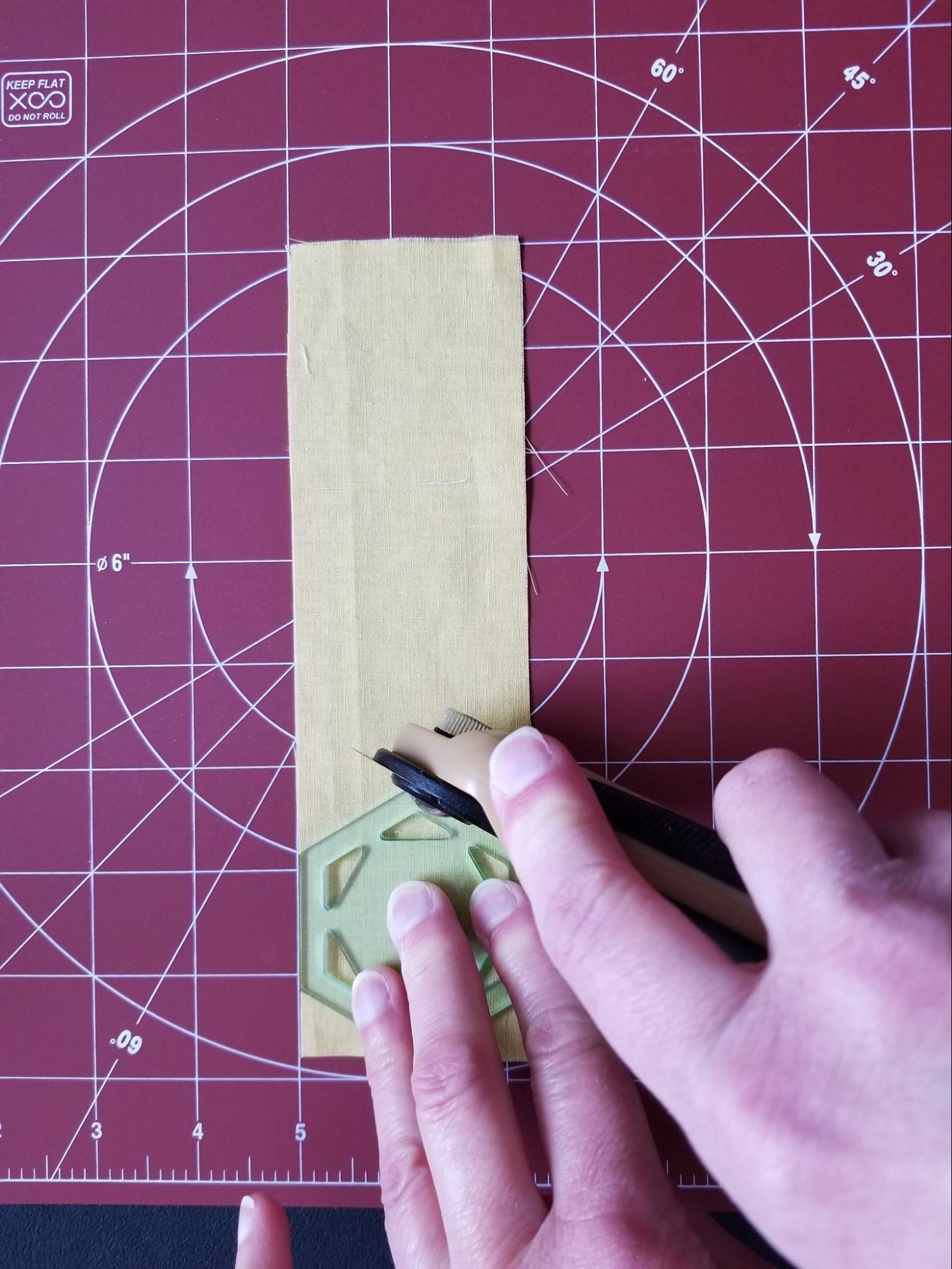 Making the first cut around a hexagon quilt template strip cutting.