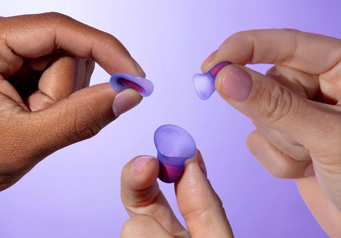 Hands holding different sizes of earplugs for night shift workers.