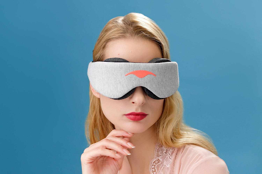 A blonde girl holding the side of her chin wearing the Manta SLEEP Mask.