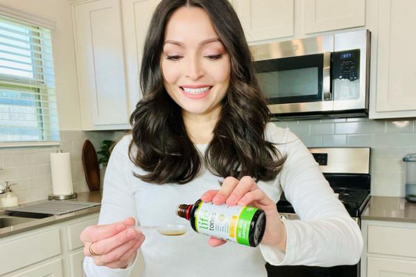 woman smiling as she measures her Lifetones Uric Acid Support Tincture.