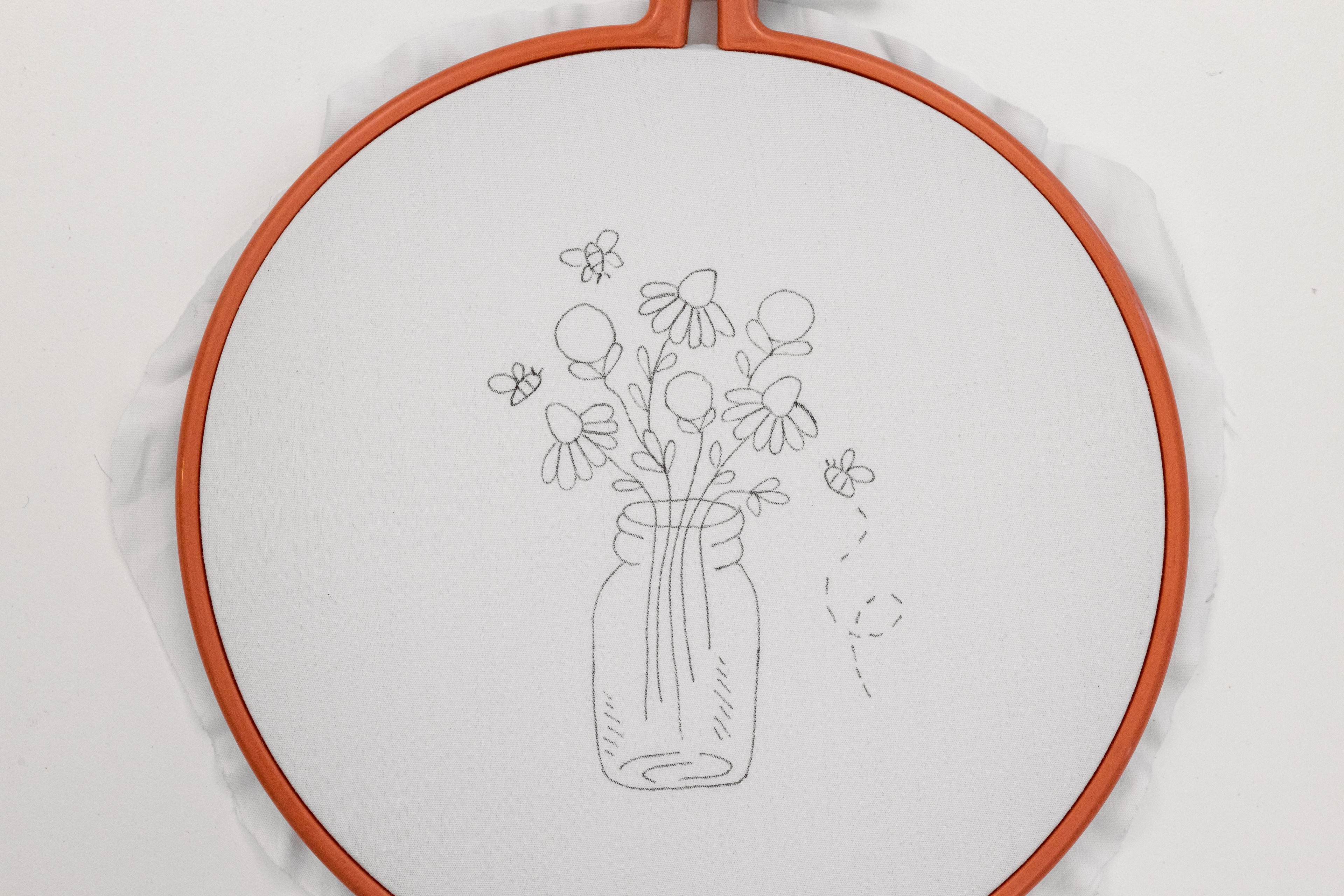 A floral vase pattern is drawn on the fabric.