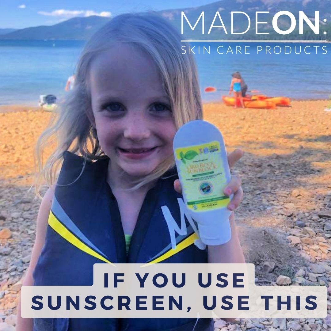 little girl holding up reef safe sunscreen at the ocean
