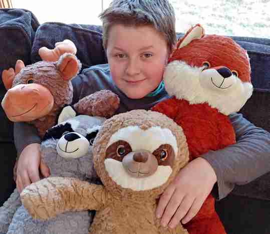 A young boy holding a bunch of stuffed animals