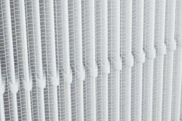 Close-up of a white radiator with vertical fins.