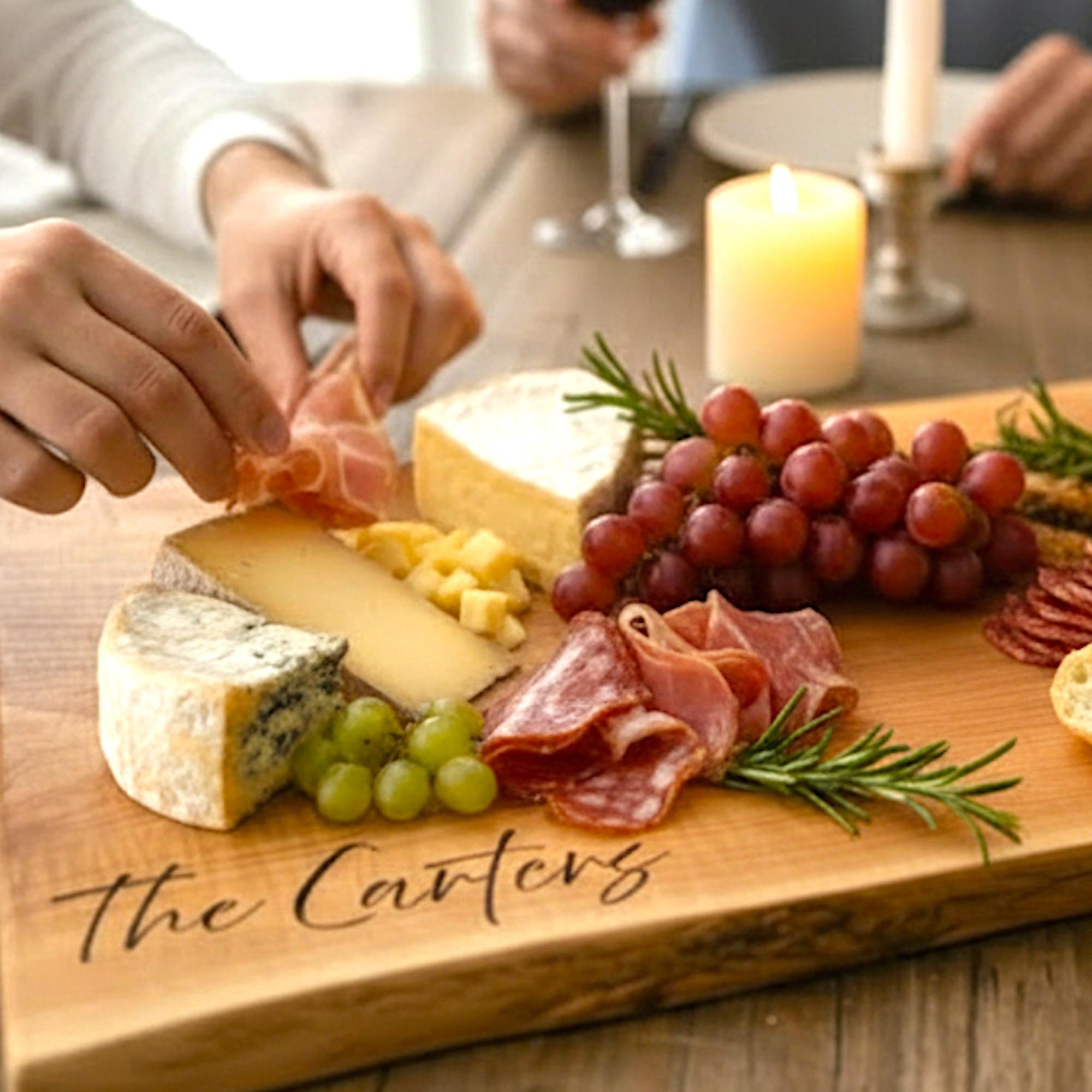 Custom engraved walnut charcuterie board styled with cheese, grapes, and wine for intimate gathering