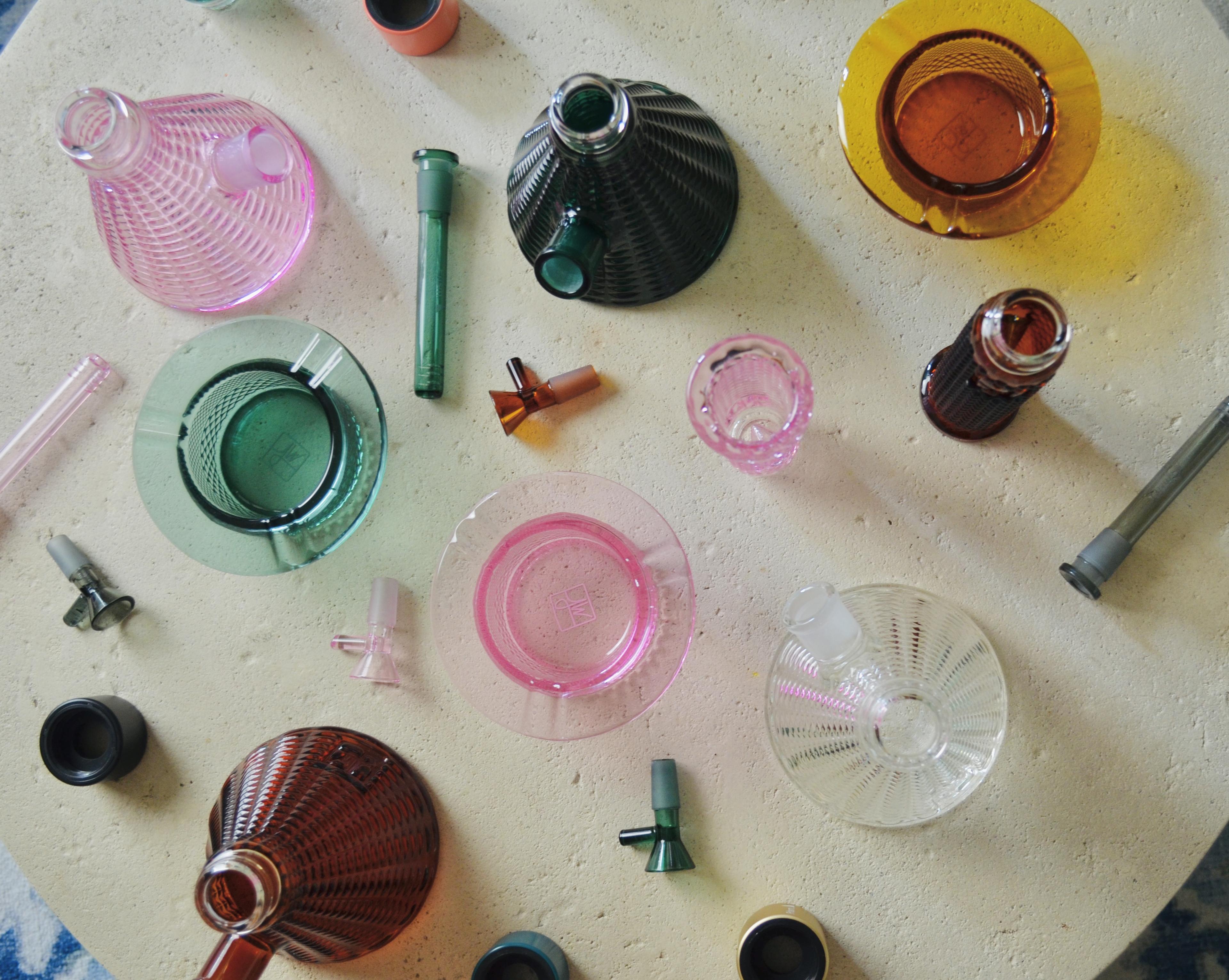 Amber Clear Teal and Pink Lemonade Prism x Jane West disassembled glassware textured glass and ashtrays on textured coffee table, bong parts, lifestyle