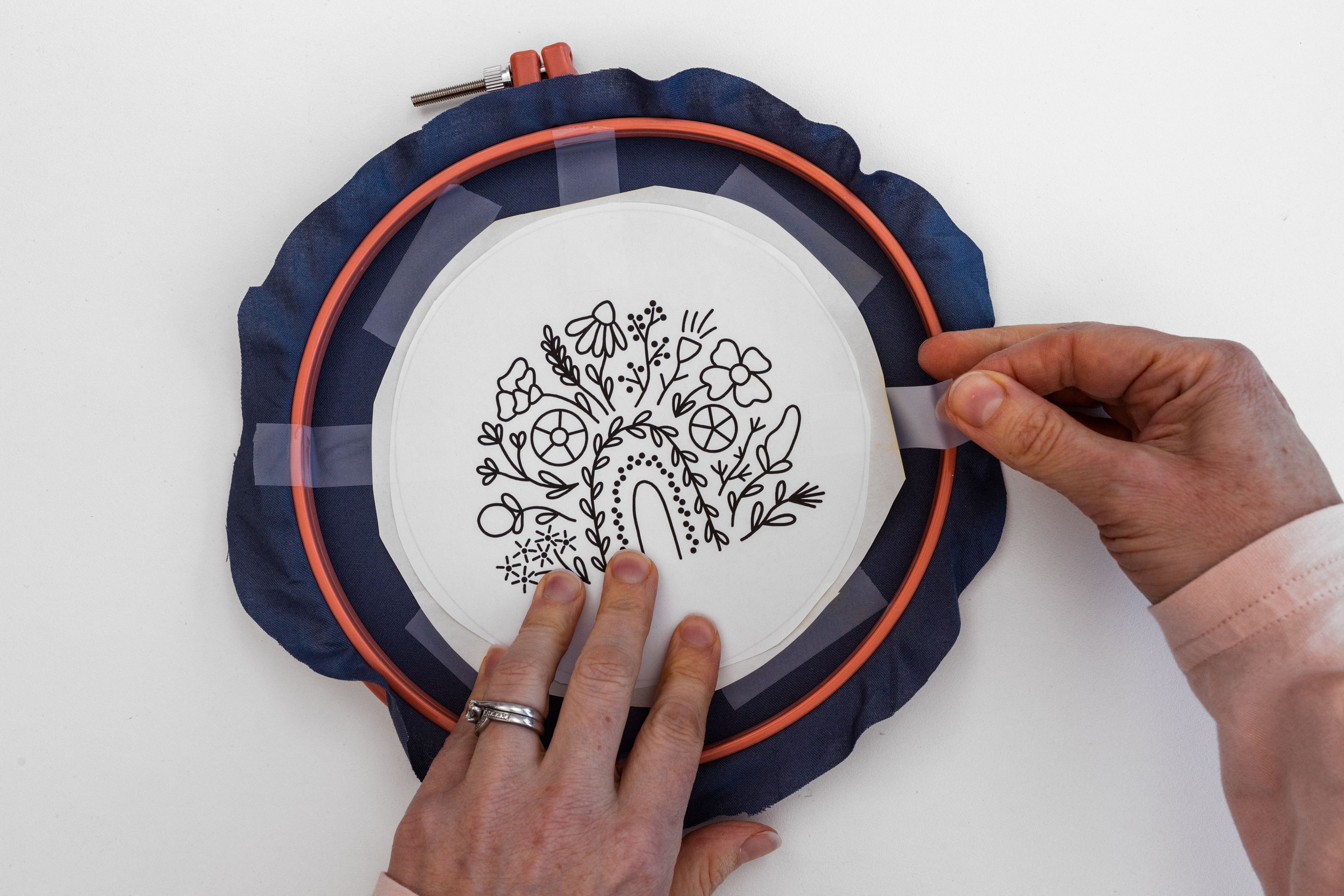 A hand cellotapes the design onto the back of the fabric.