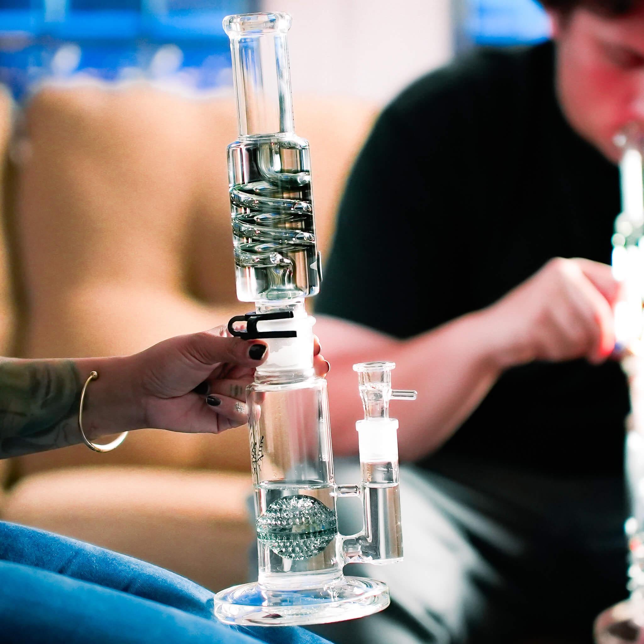 hands passing glass recycler bong