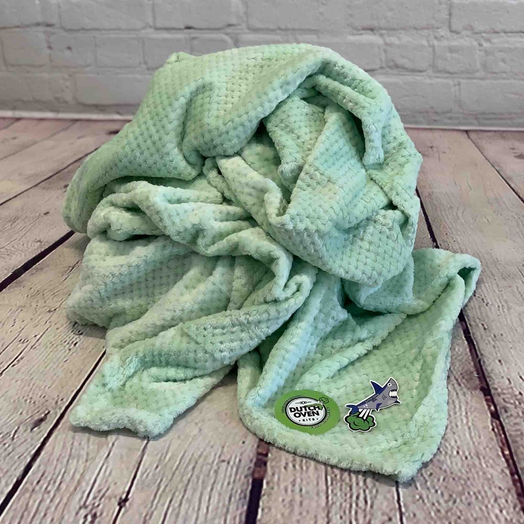 picture of a light green throw blanket on a wood background