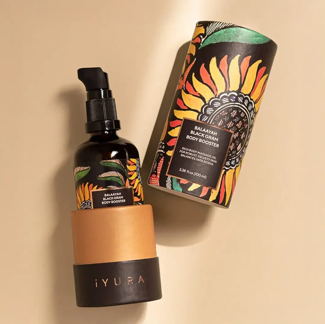 A bottle of Yauvari amplified youth spring surrounded by ingredients like black gram, cut in half limes, neroli flowers with it's buds and leaves.
