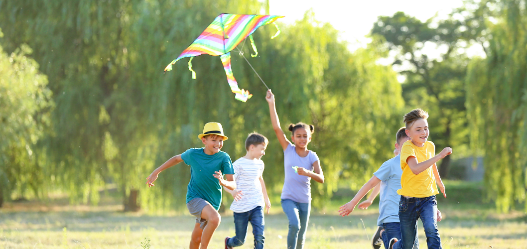 kids running flying kite in park