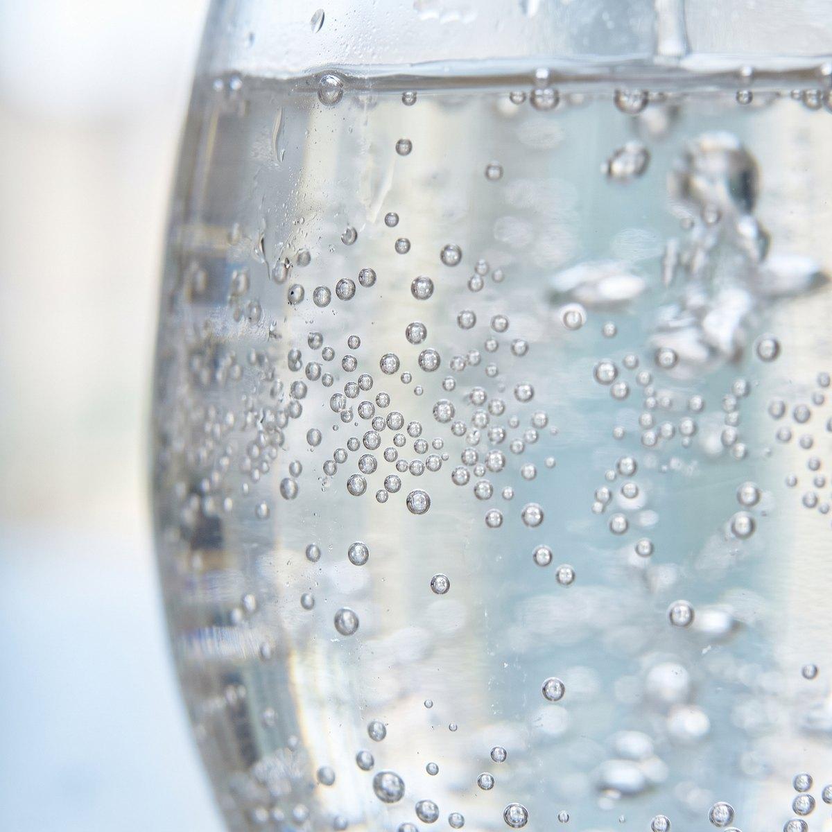 Close-up of tiny bubbles rising through a glass of water