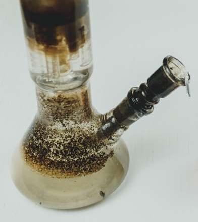 Close-up of a neglected beaker bong with a tree percolator, completely overgrown with thick, mottled mold and black goo. This image illustrates the "Mold Colony" horror story, emphasizing the extreme biohazard and the severe health risks of using a fungally contaminated, uncleanable piece of glass.