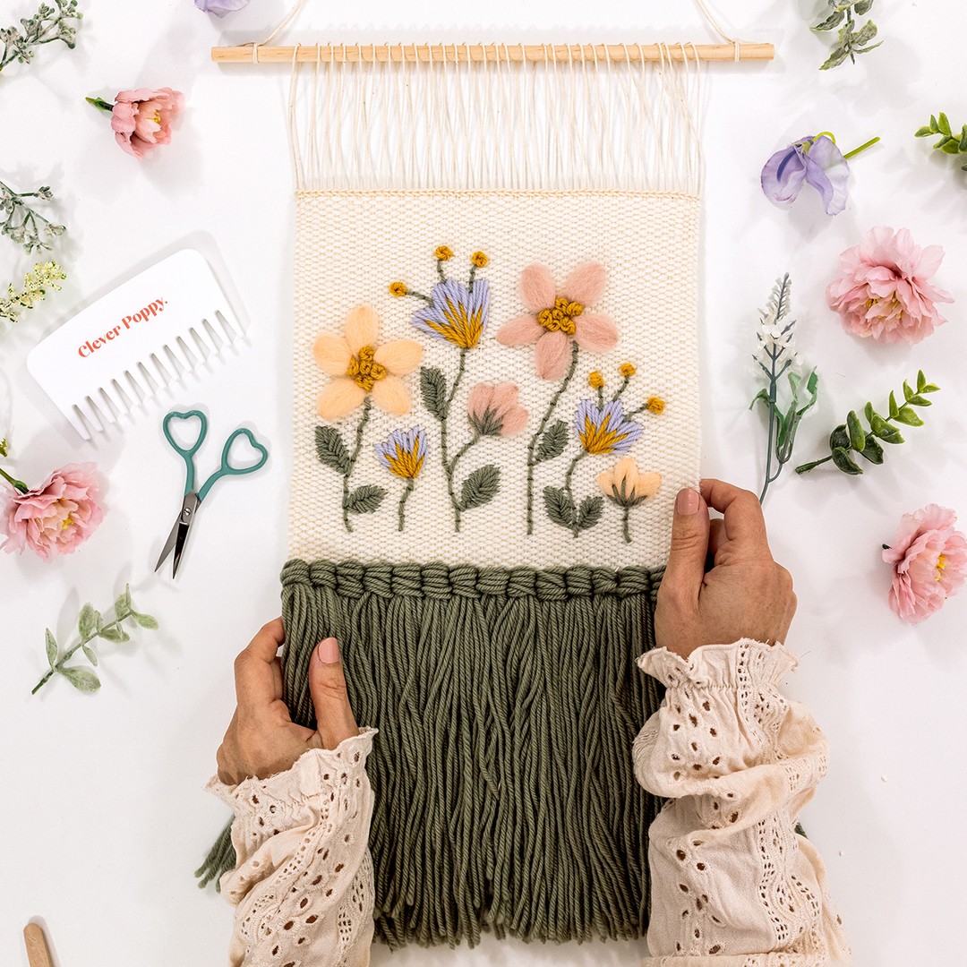 Hands hold the weaving pattern 'Woven Meadow' which uses embroidered details with wool.
