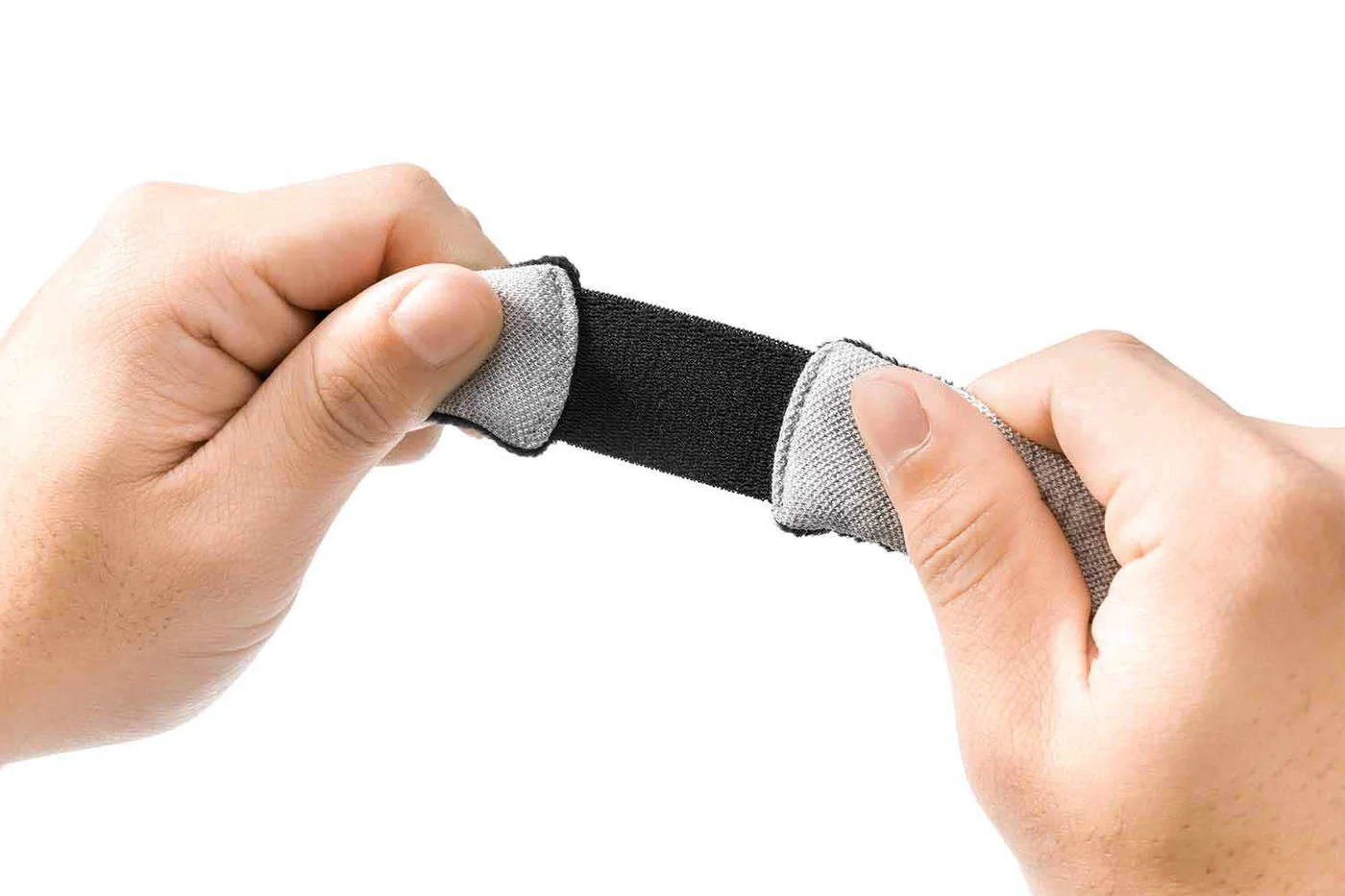 Hands stretching the black elastic of a gray sleep mask’s head strap