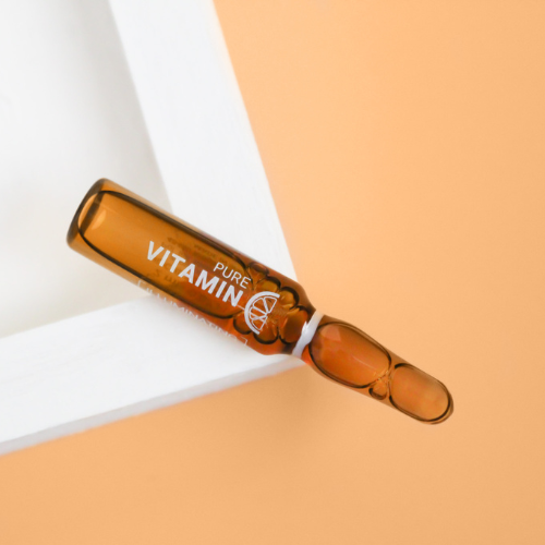 sliced oranges and many Vitamin C Ampoules laying on a bright orange background.