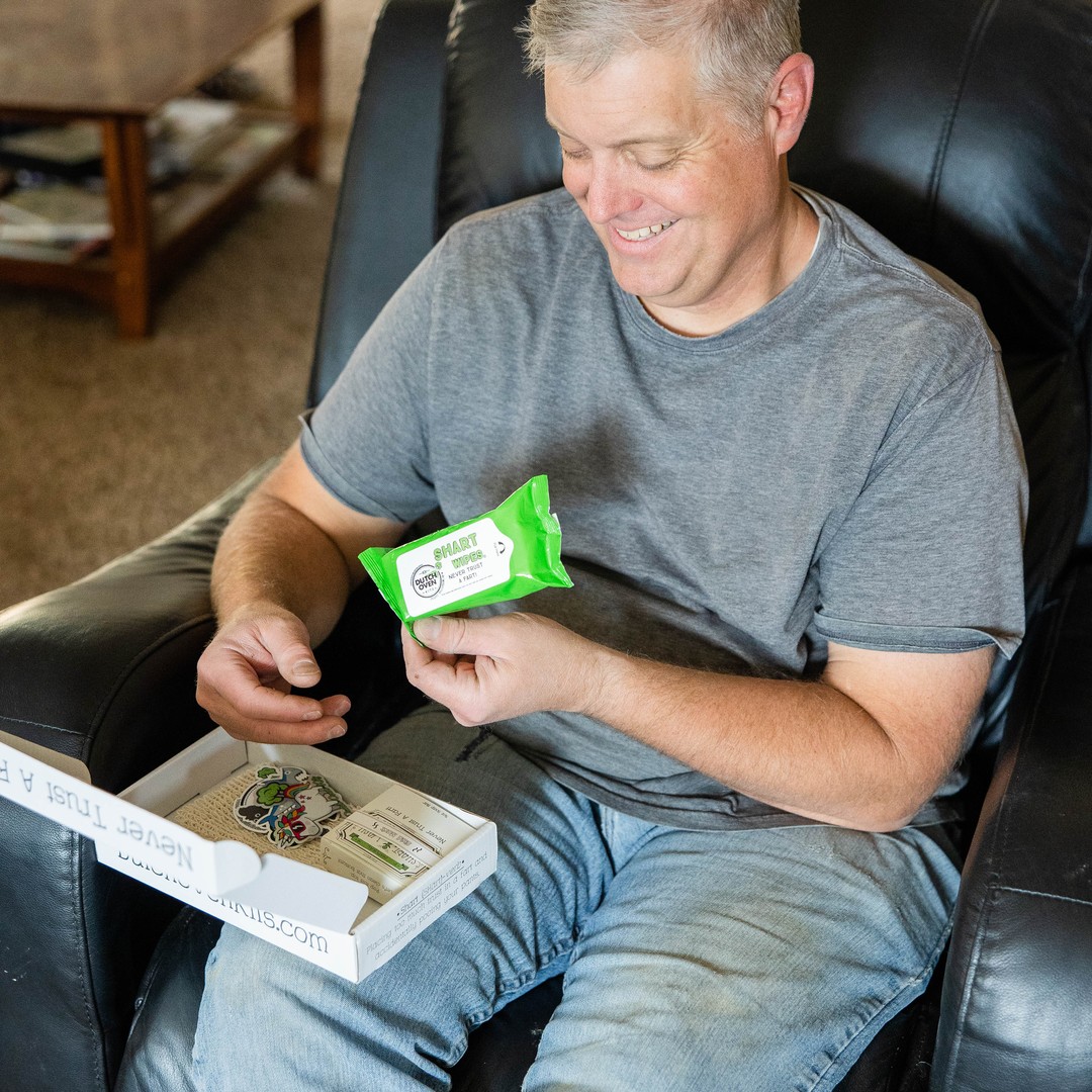 A man smiling while opening a shart wash emergency kit gift box