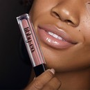 Medium skin tone model holding up Nude Pout to lips and smiling