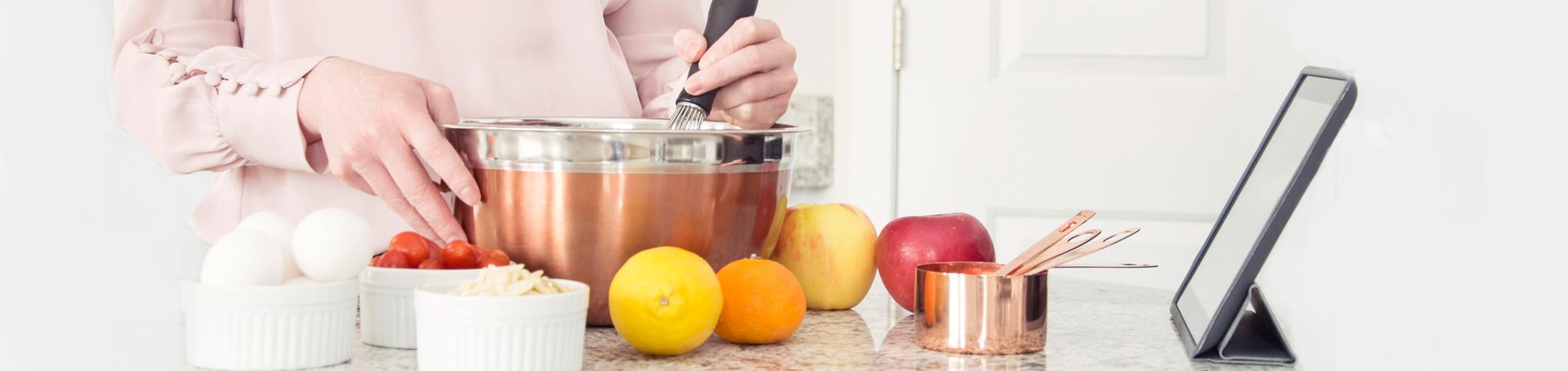 A woman mixing together ingredients with an iPad