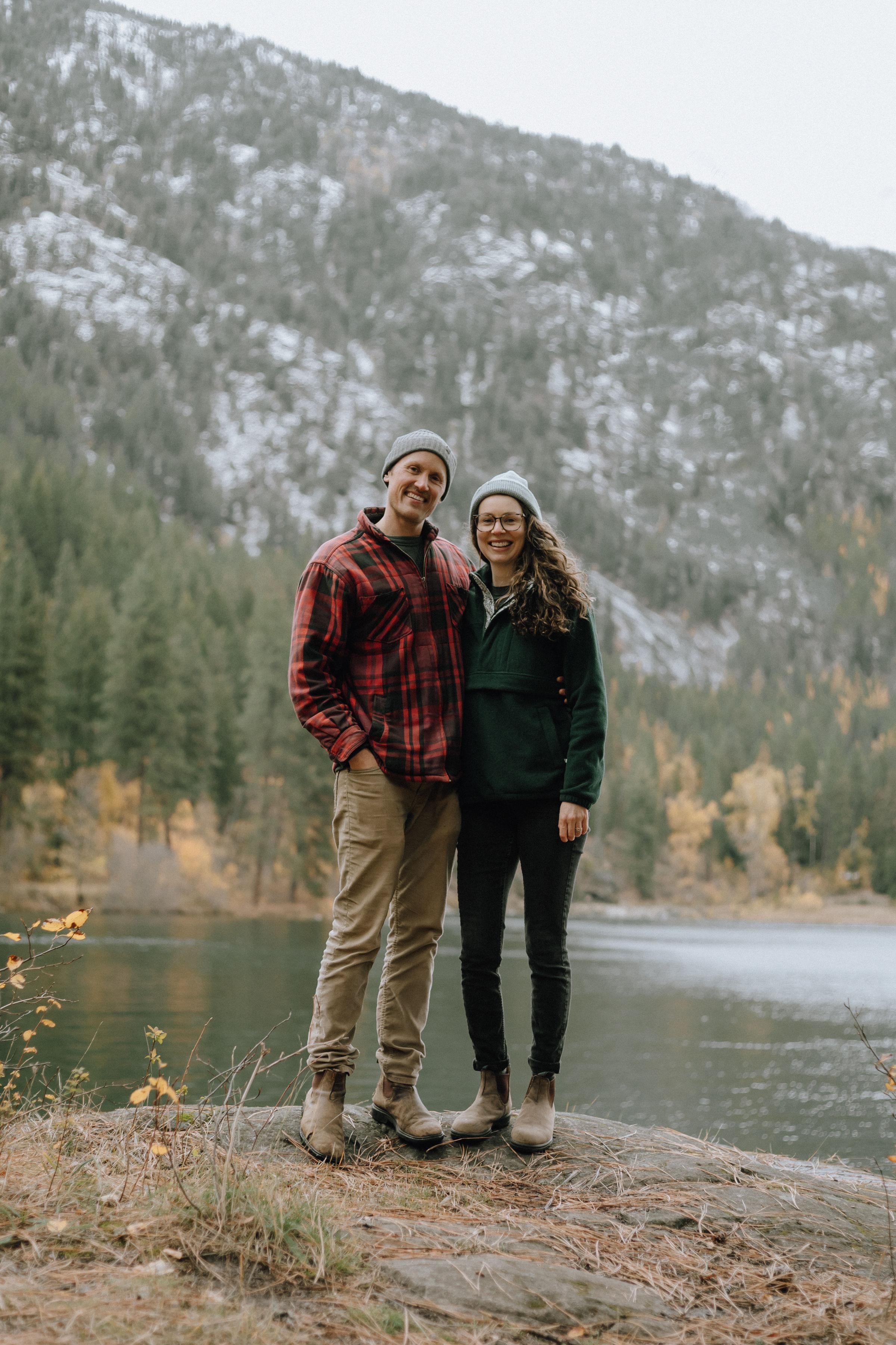 Owners of Wildelore, Chas and Carissa standing in front of Water surrounded by mountain