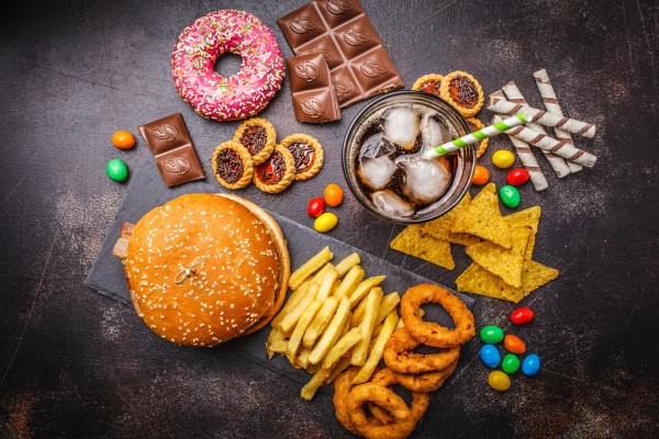 image displaying various junk foods (cheeseburger, fries, donut, chocolate, onion rings, chips) and soda