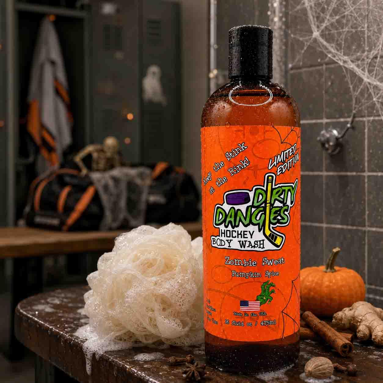A bottle of Dirty Dangles Hockey Body Wash in Zombie Sweat, Pumpkin Spice scent on a locker room shower bench with pumpkin spice Halloween props and spiderwebs.