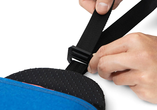 Hands pulling the black strap of a nap pillow to adjust the height.