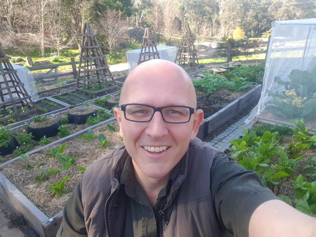 Brian smiling in a raised vegetable garden.