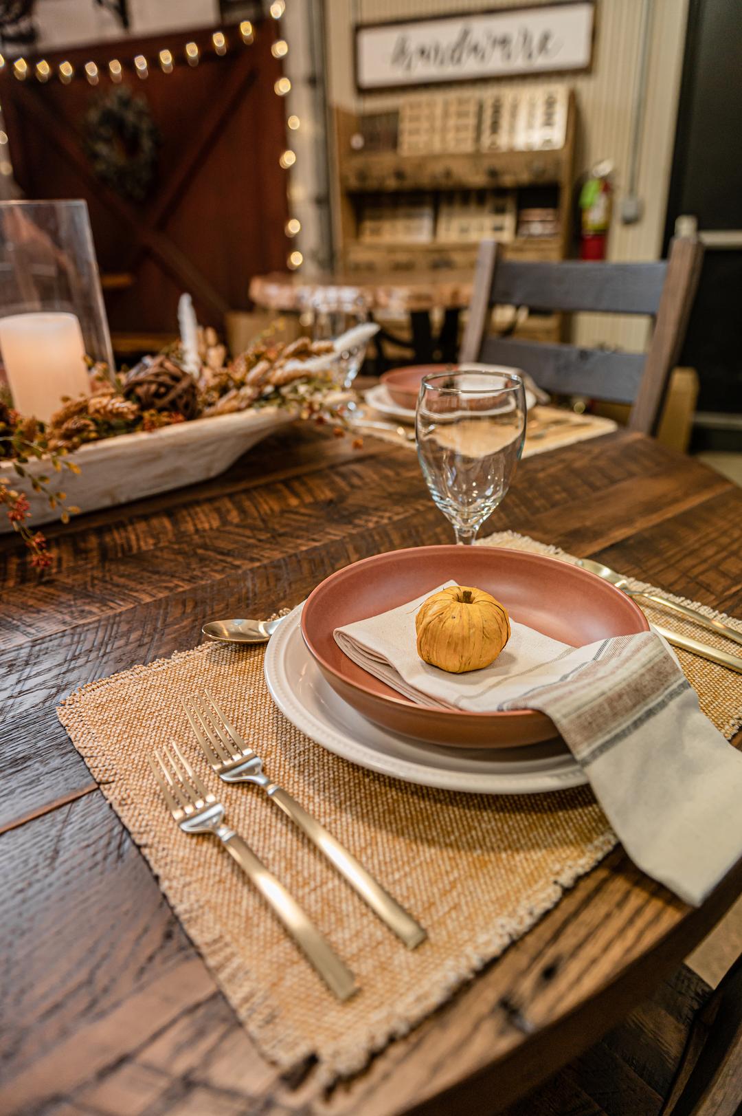 pumpkin color placemats and cream-toned plates with terracota soup bowl and pumpkin decoration