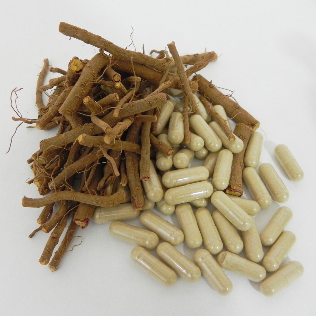 Ashwagandha root in a small pile next to a small pile of capsules
