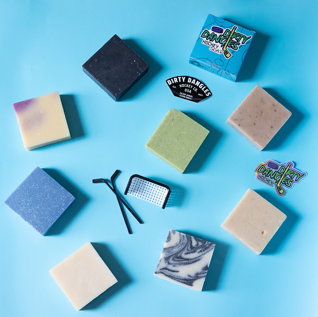 8 soap bars on a blue background with a dirty dangles soap box and stickers