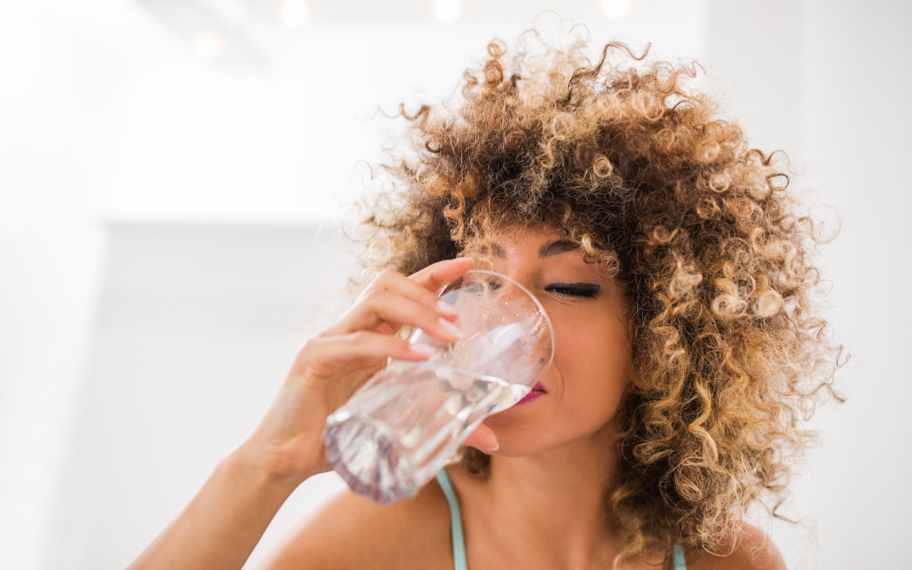 black woman with naturally curly hair drinking water