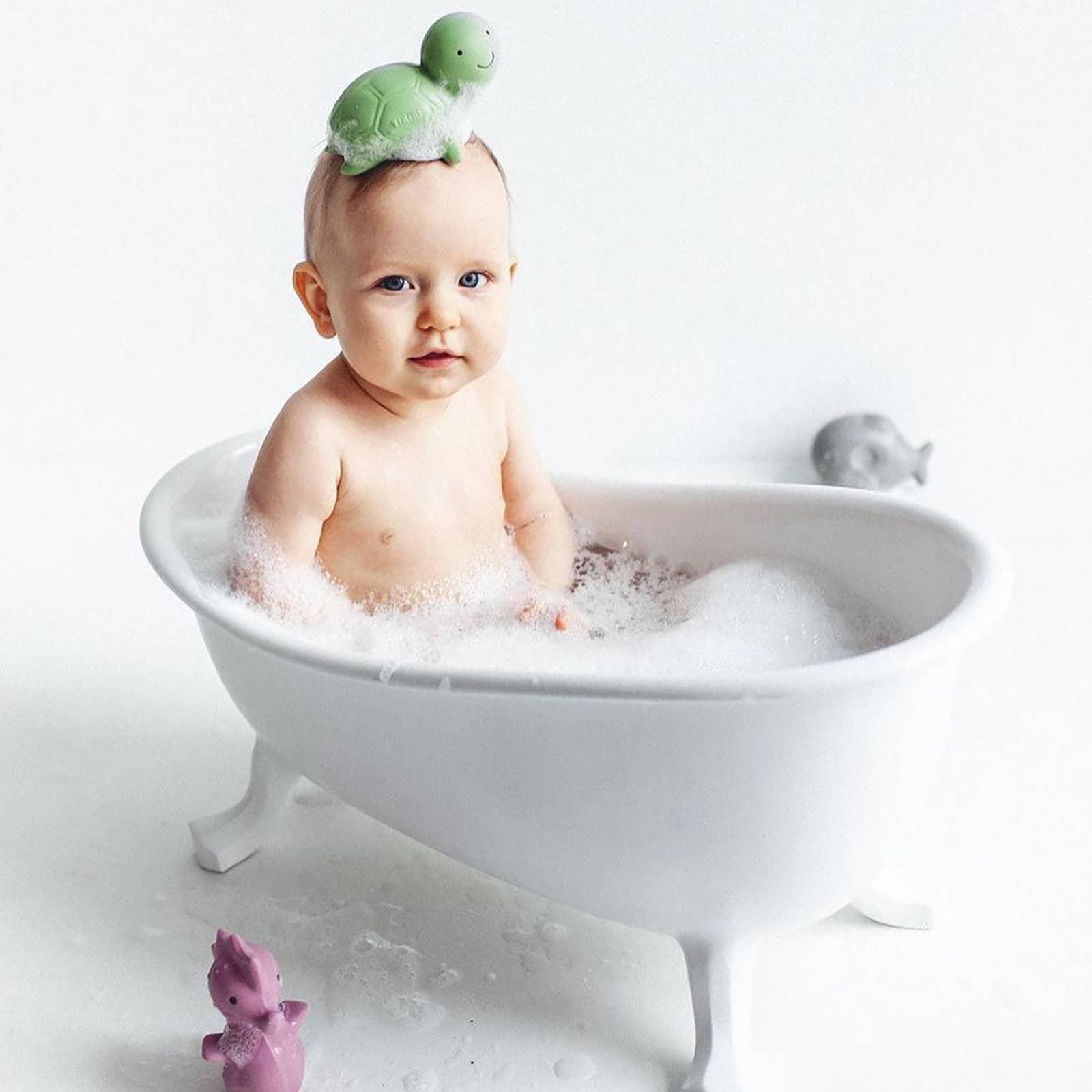 A wooden bucket and brush with several colorful rubber bath toys around it.
