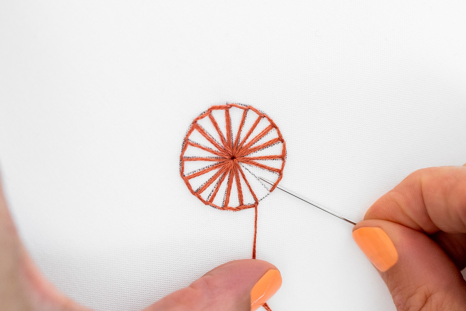 A buttonhole wheel shape is being created on embroidery fabric.