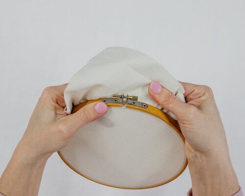 This image shows step 3 of dressing your hoop, pulling the fabric tight in the hoop .