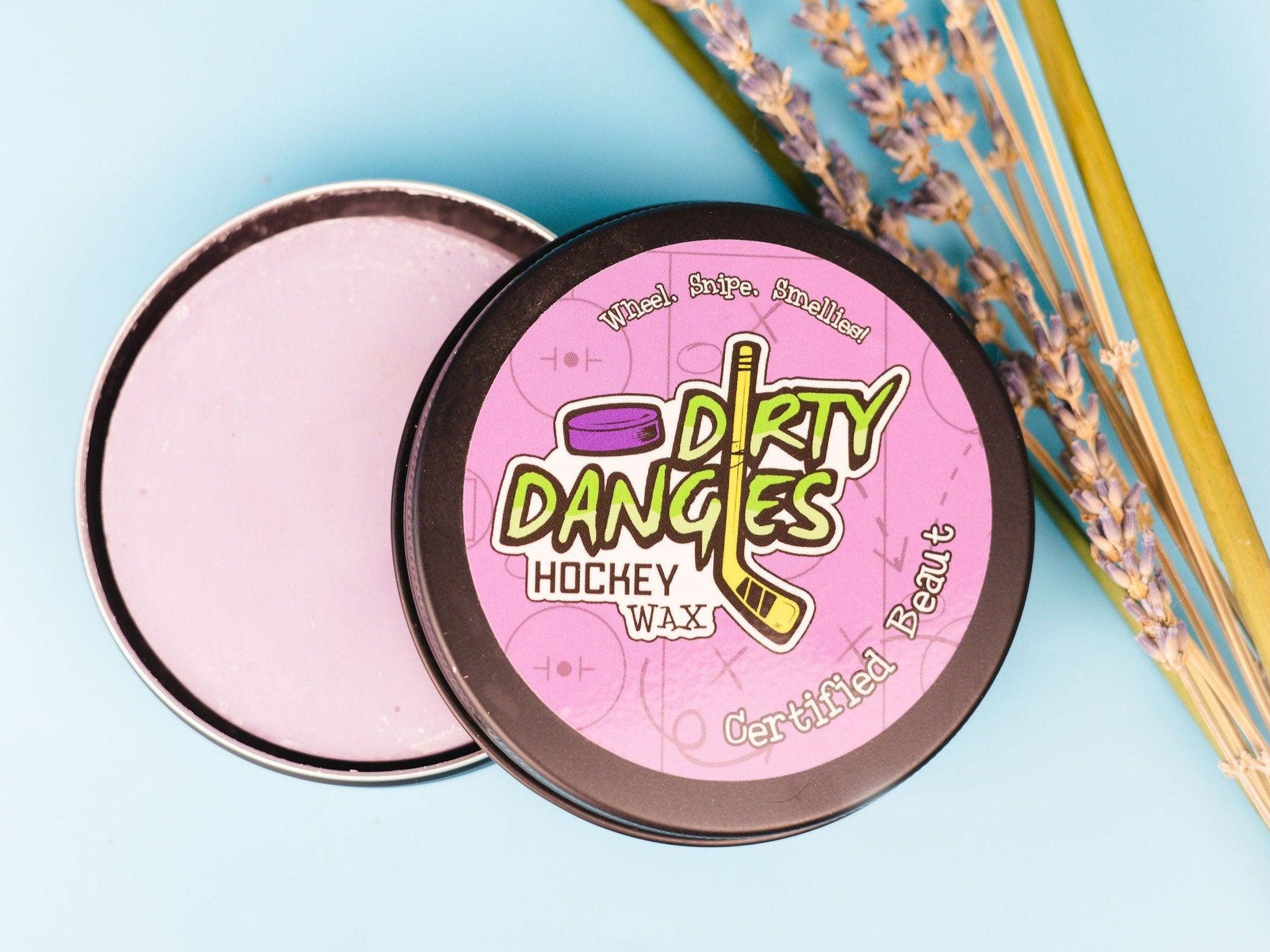 A tin of dirty dangles girls and womens hockey stick wax on a blue background with lavender and lemongrass