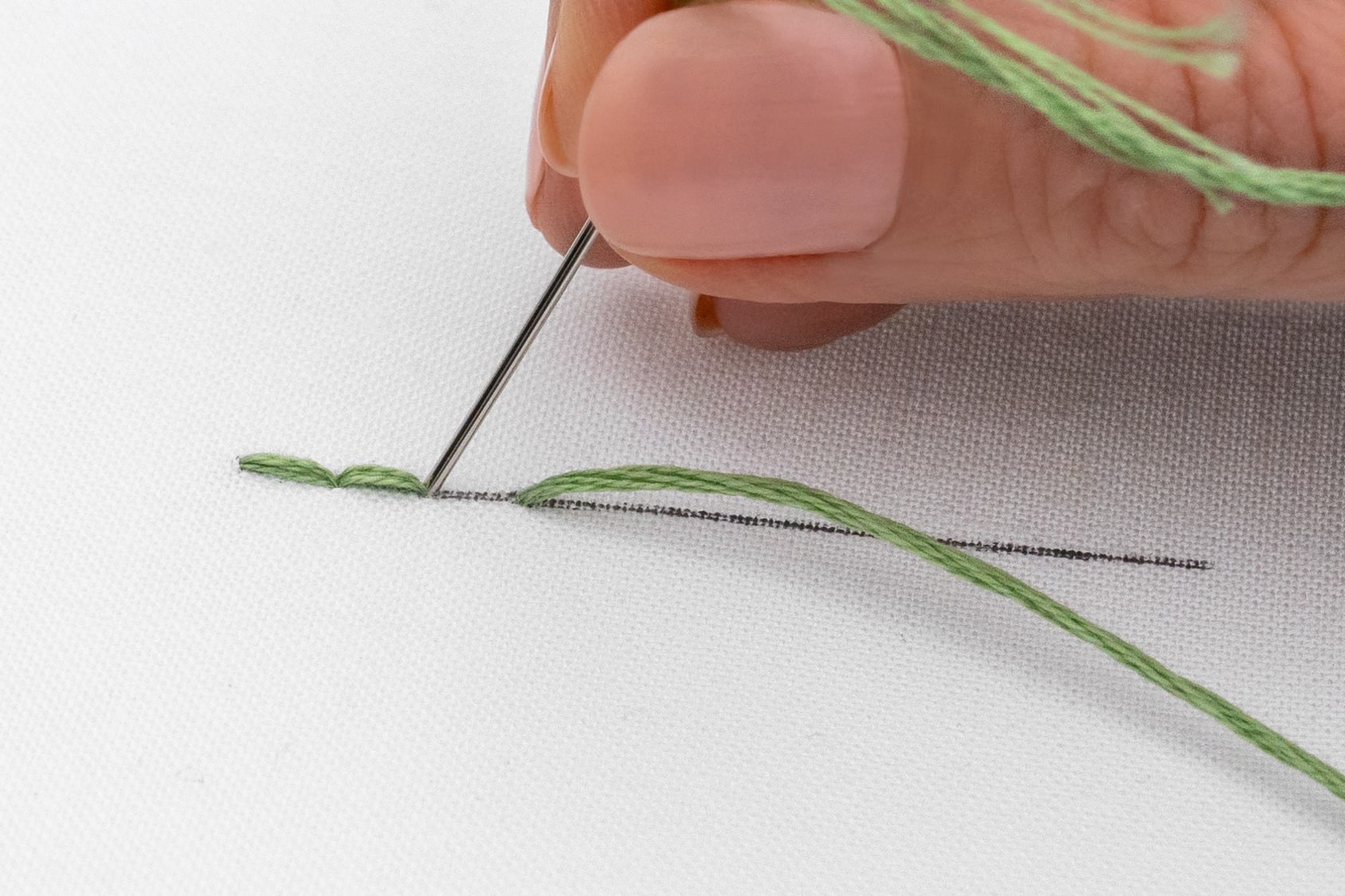 A needle is brought down to create a third stitch,