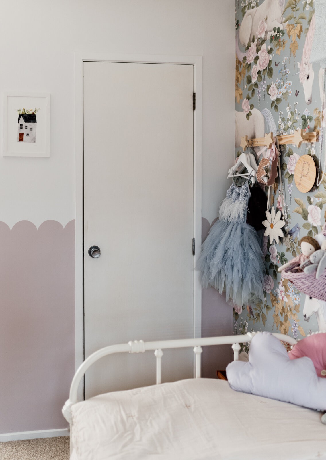 A child's bedroom is painted with a mauve and white scalloped wall effect and adorned with children's decor.