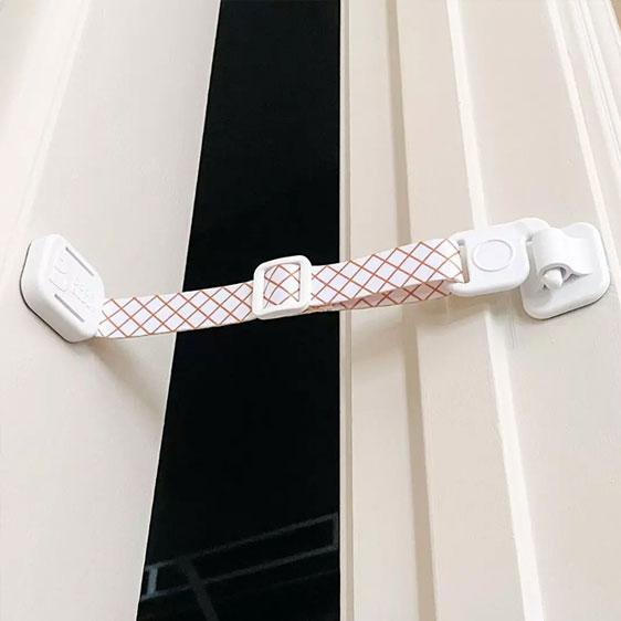 Door Buddy door strap installed on an interior door creating a small adjustable opening that allows cats through while keeping dogs and toddlers out.