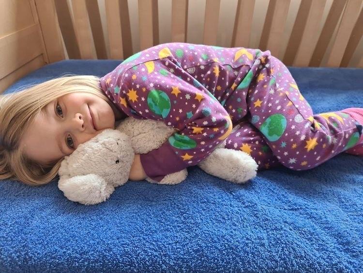 Girl in pyjamas laying in bed on a PeapodMat