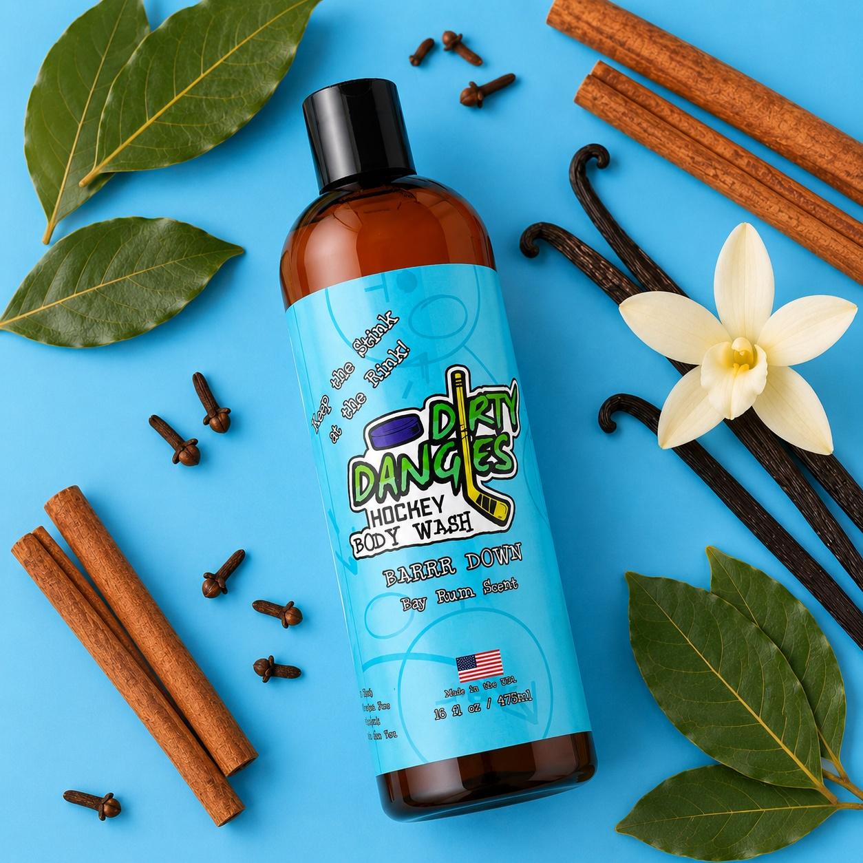 a bottle of dirty dangles barrr down bay rum scented hockey body wash on a blue background with bay leaves, spices and vanilla beans.