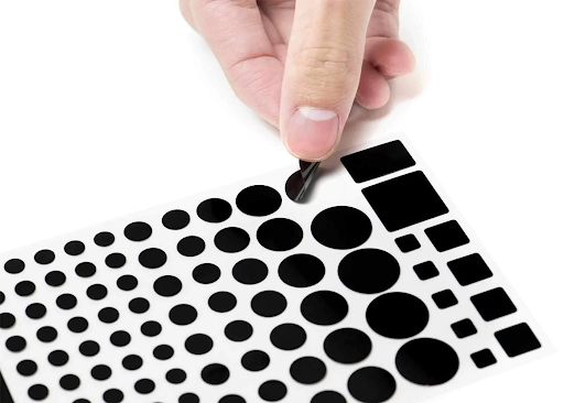 A hand peeling off one sticker from a sheet of blackout stickers.